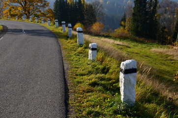 mountain road with traditional white stone bollards with a black stripe. Old stone pillars of...