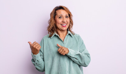 middle age woman smiling cheerfully and casually pointing to copy space on the side, feeling happy and satisfied © kues1