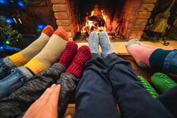 Happy family wearing warm socks in front of cozy fireplace during Christmas Time - Focus on socks