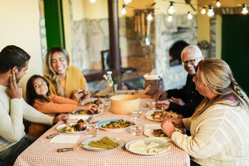Happy latin family having fun eating together at home - Focus on grandmother head