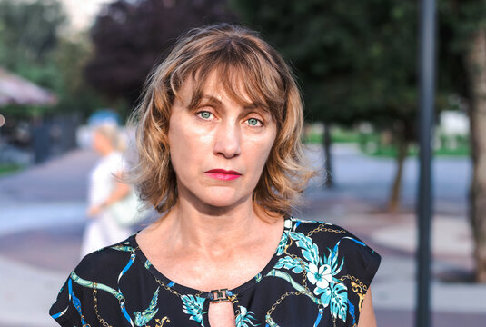 portrait of a beautiful mature woman of middle age 50 years old with blond hair with a pensive look, in the park