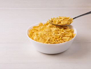 cornflakes with milk in bowl on table, closeup