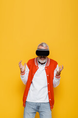 middle aged man in bomber jacket and vr headset gesturing isolated on yellow