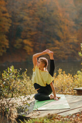 Obraz premium A young beautiful blonde woman does yoga in nature