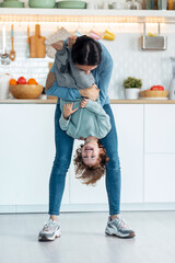 Young beautiful mother playing and having fun on the floor with her son in living room at home.