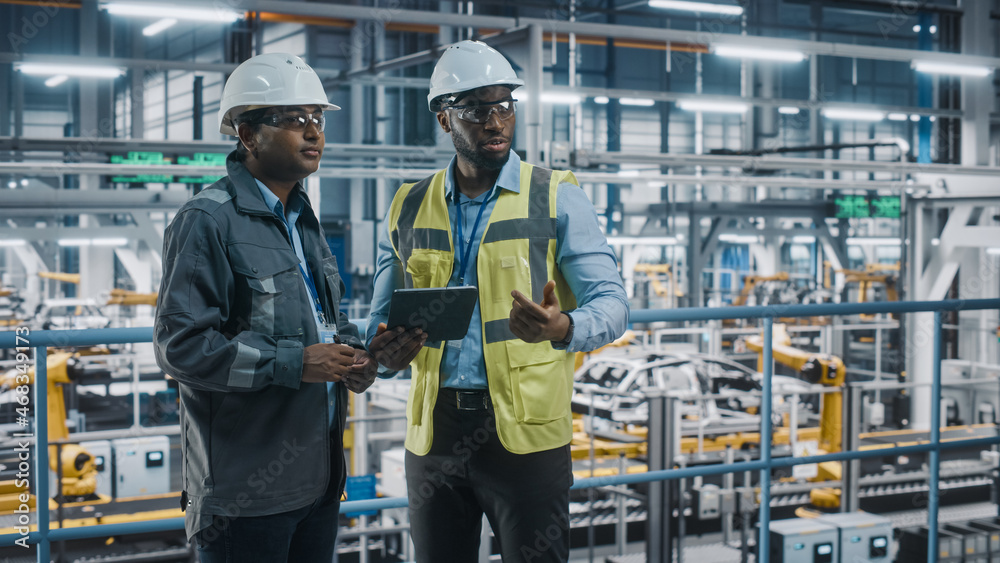 Leinwandbilder multiethnic manager and african american car factory engineer in uniform using tablet computer. auto
