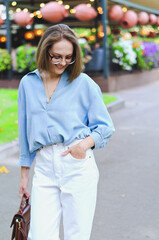 Urban portrait of young attractive business woman in eye glasses and casual clothes. Woman walking in the city street, park, talking on her phone, making selfie, works in sunny day.