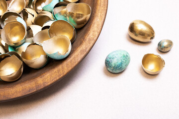 A festive Easter background with lots of golden eggshells and beautiful, modernly colored eggs. Golden eggs as a concept of wealth and success. An original idea for handmade Easter decor. Copy space.