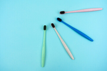 Colored toothbrushes made from recycled plastic on a light blue background with copy space. Top view