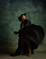 Full-length portrait of fearless brutal man, medeival pirate in hat and cloak with sword isolated...