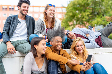 Happy millennial friends making a video recording, people using smartphone and modern technology to communicate, post pandemic period and facemask on arm, vaccinated people against covid19