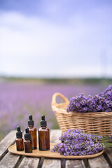 Essential lavender oil in the bottle with dropper on the gray wooden desk. Vertical close-up.