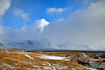 Budir in the background snow-capped and misty mountains and bay, Iceland