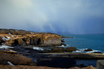 cliff edge and black basalt rocks in the blue sea grey fog , Lóndrangar, Iceland