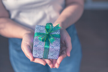 Close up shot of Female hands holding gift box. Copyspace. Christmas, hew year, birthday concept. Festive background with bokeh and sunlight. Magic fairy tale. Shallow depth of field with focus on box