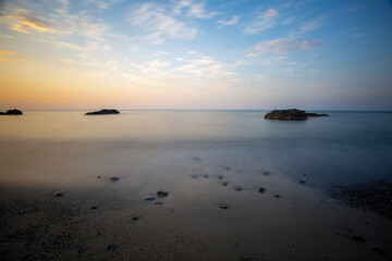 sunset pebbles and rocks on the beach long exposure in the sea