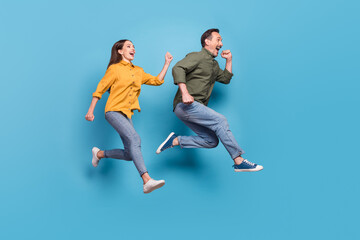 Fototapeta na wymiar Full length photo of brown haired husband wife jump up run empty space sale isolated on pastel blue color background