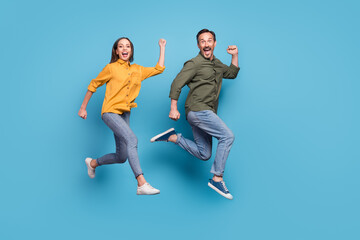 Fototapeta na wymiar Full size profile photo of two delighted persons raise fists celebrate success triumph isolated on blue color background