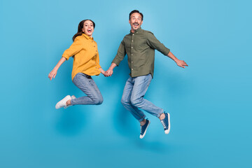 Fototapeta na wymiar Full size photo of mature cheerful man and woman jump up husband wife enjoy isolated on blue color background