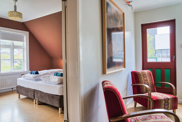 Cosy and quiet room with walls covered with warm colours and ecological atmosphere with recycled objects and furniture. Family room. Shared hostel room. Nordic atmosphere and decoration. Natural light