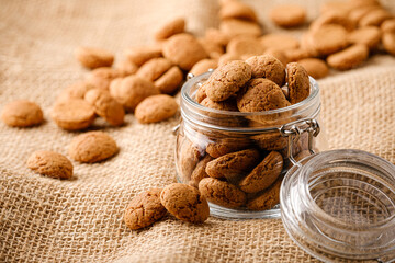 Kruidnoten cookies in glass jar on sackcloth. Pepernoten, traditional sweets, strooigoed. Dutch holiday Sinterklaas greetings card concept of Saint Nicholas day with copy space.