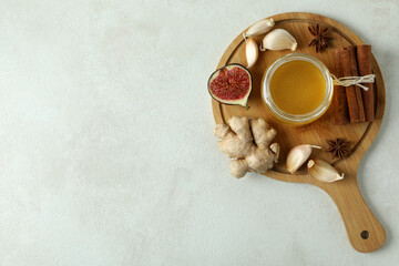 Concept of treatment colds with honey and garlic on white textured background