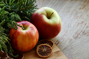 Christmas decoration with red apples, fir and dried oranges.