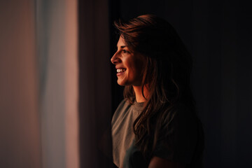 Attracive adult woman, looking through the window