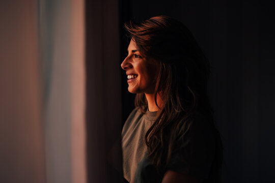 Attracive adult woman, looking through the window