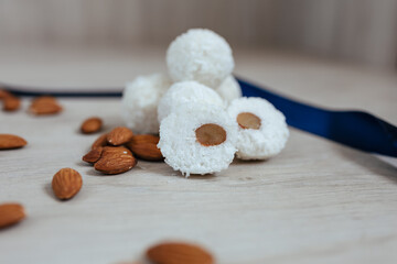 Chocolate sweets with coconut flakes, almonds and cream on wooden background.