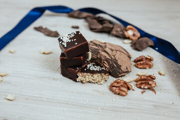  Dark chocolate sweets with nuts, caramel and fruits on wooden background.