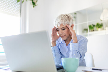 Mature business woman concerned thinking about online problem.Frustrated worried senior middle aged female suffering from memory loss, having a headache.