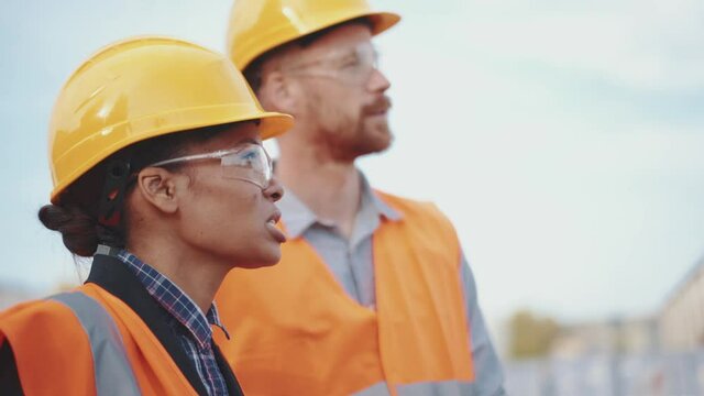 Positive multinational engineers discussing a working project outdoors