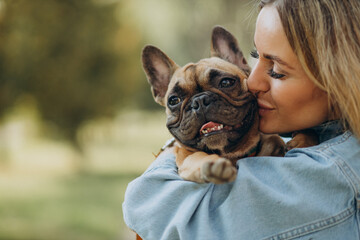 Young woman with her pet french bulldog in park - obrazy, fototapety, plakaty