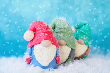 Christmas card three figures of funny gnomes, covered with snow, stand one after another on a blue...