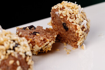 Beautiful candies with sesame seeds on a white plate on a black background