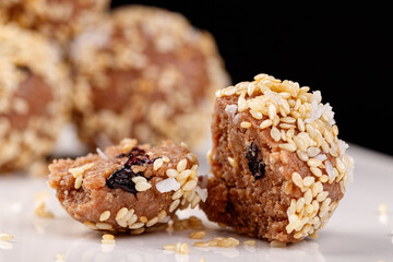 Beautiful candies with sesame seeds on a white plate on a black background