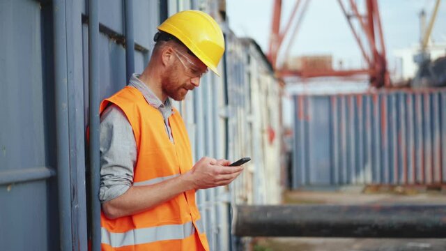 Handsome man shipbuilder in uniform leafing tape at phone