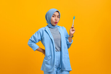 Fototapeta na wymiar Attractive young Asian woman holding pen and have a great idea isolated over yellow background