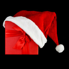 Santa Claus hat dressed on a corner of a gift red box on a black background. Top view