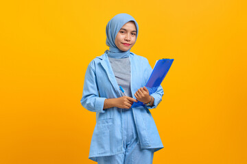 Happiness young Asian woman holding document folders isolated over yellow background