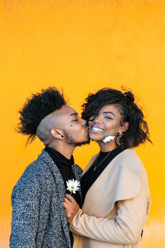 African American transgender couple smiling, with flower in her mouth, hanging out in front of blank wall with copy space