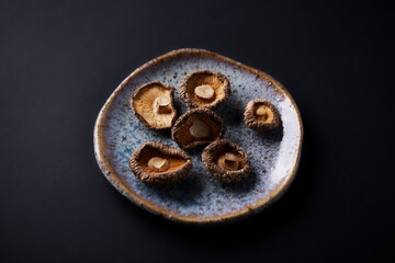 Dried Shiitake Japanese Mushrooms on dark paper background. Close up. Copy space.	