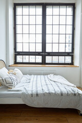 Interior of contemporary bedroom with new comfortable bed and wooden shelves in flat designed in...