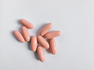 Group of pink capsules on the white background. Vitamins for women care.