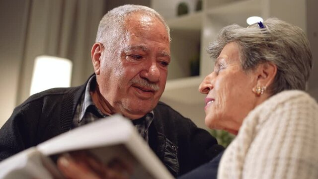 Elderly couple emotional moments. Elderly husband and wife looking at photo album. Being a family, getting old, going back to the past. Happy moments. Slow motion. Slow motion.
