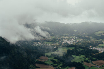 Aerial view of a village between mountains with forests on a foggy day