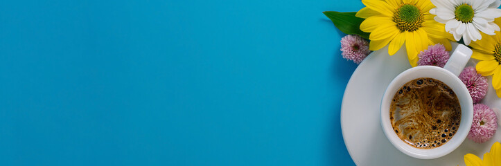 white coffee cup with espresso, flowers on a blue background with free space for text