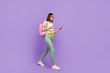Full body profile side photo of young girl walk look mobile hold book academic courses isolated over purple color background