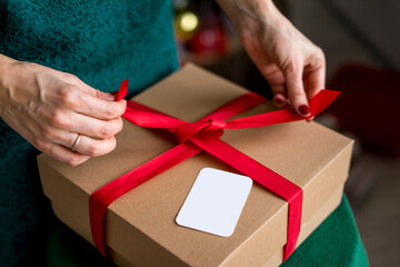 Packing Christmas gifts.Three Christmas gift boxes wrapped in kraft paper tied with red string and getting card